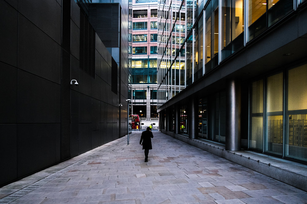 person walking on path between high rise office buildings