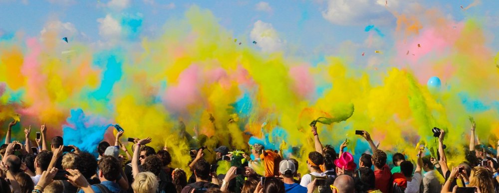 crowd with colourful powder paints in air above heads