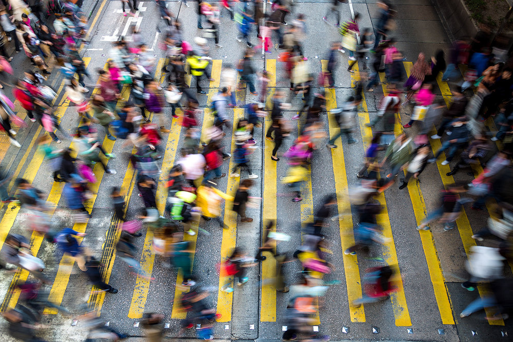 crowd of people crossing yellow zebra crossing on road